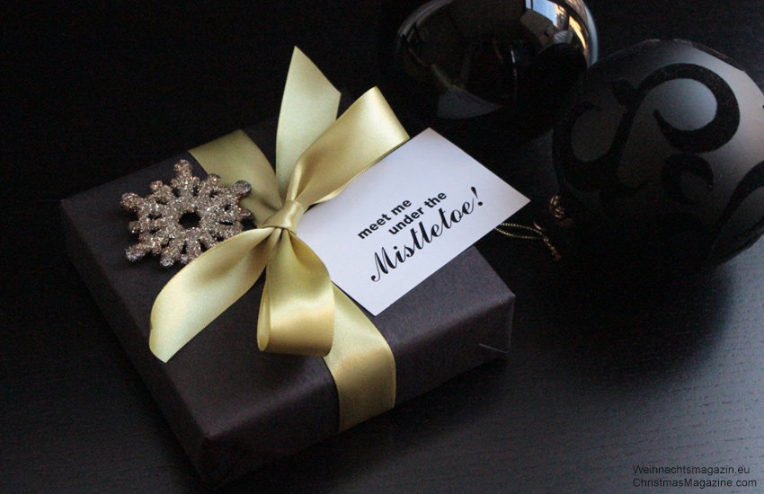 gift wrapped in black with mistletoe gift tag