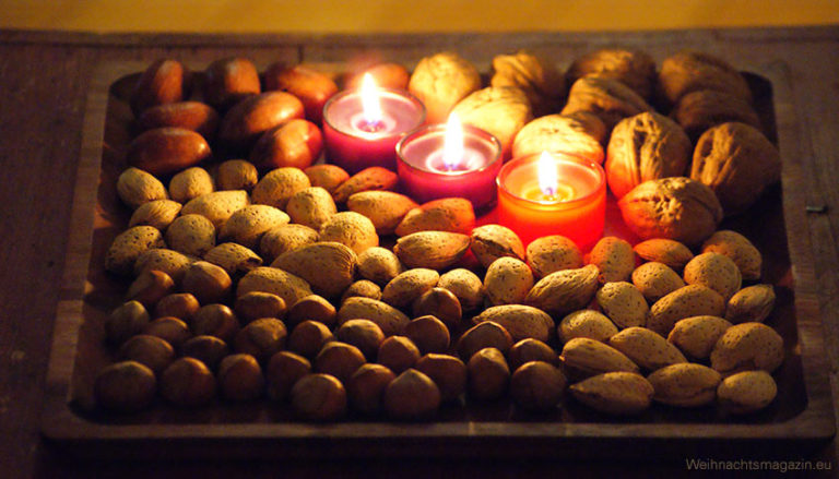 a diplay on wooden tray with geometrically arranged nuts and red tealights