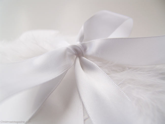 present wrapped in white with feathers and satin ribbon