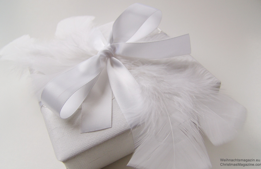 Christmas present wrapped in white, feathers, satin ribbon